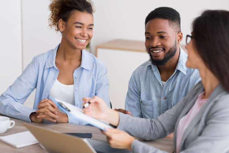 Uma mulher apresentando uma prancheta para um homem e uma mulher sorridentes